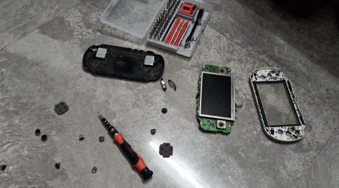 A disassembled PSP mid-repair, laid out with tools